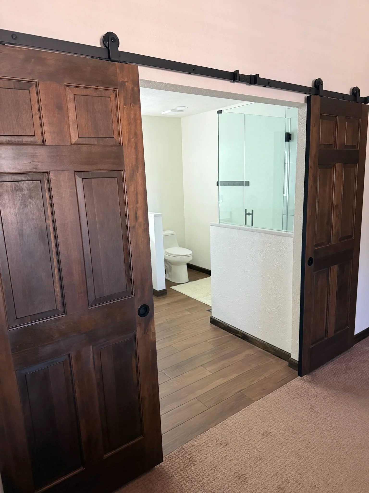 Bathroom with dual wood sliding barn doors, glass shower enclosure, and tile flooring