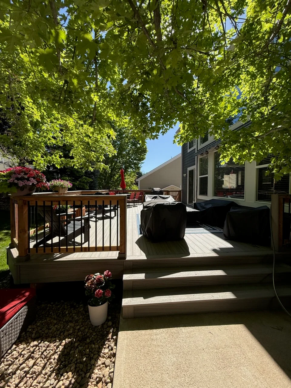 Composite deck with black railings, planter boxes, and concrete walkway leading to home