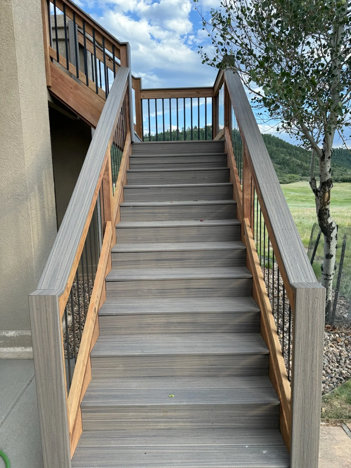 Composite deck stairs with metal railing and wood handrails leading upward