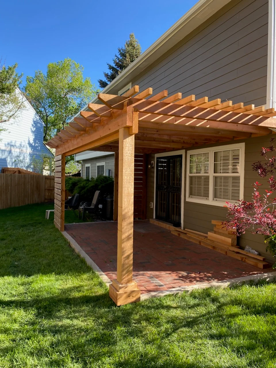 Cedar pergola with timber posts and lattice roof over brick patio