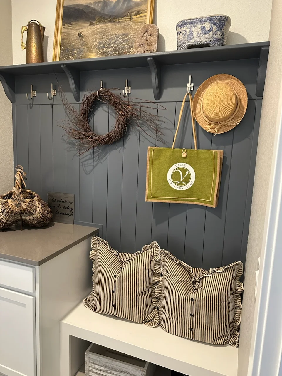Charcoal gray shiplap wall with three shelves, nickel hooks, and white base bench for entryway storage