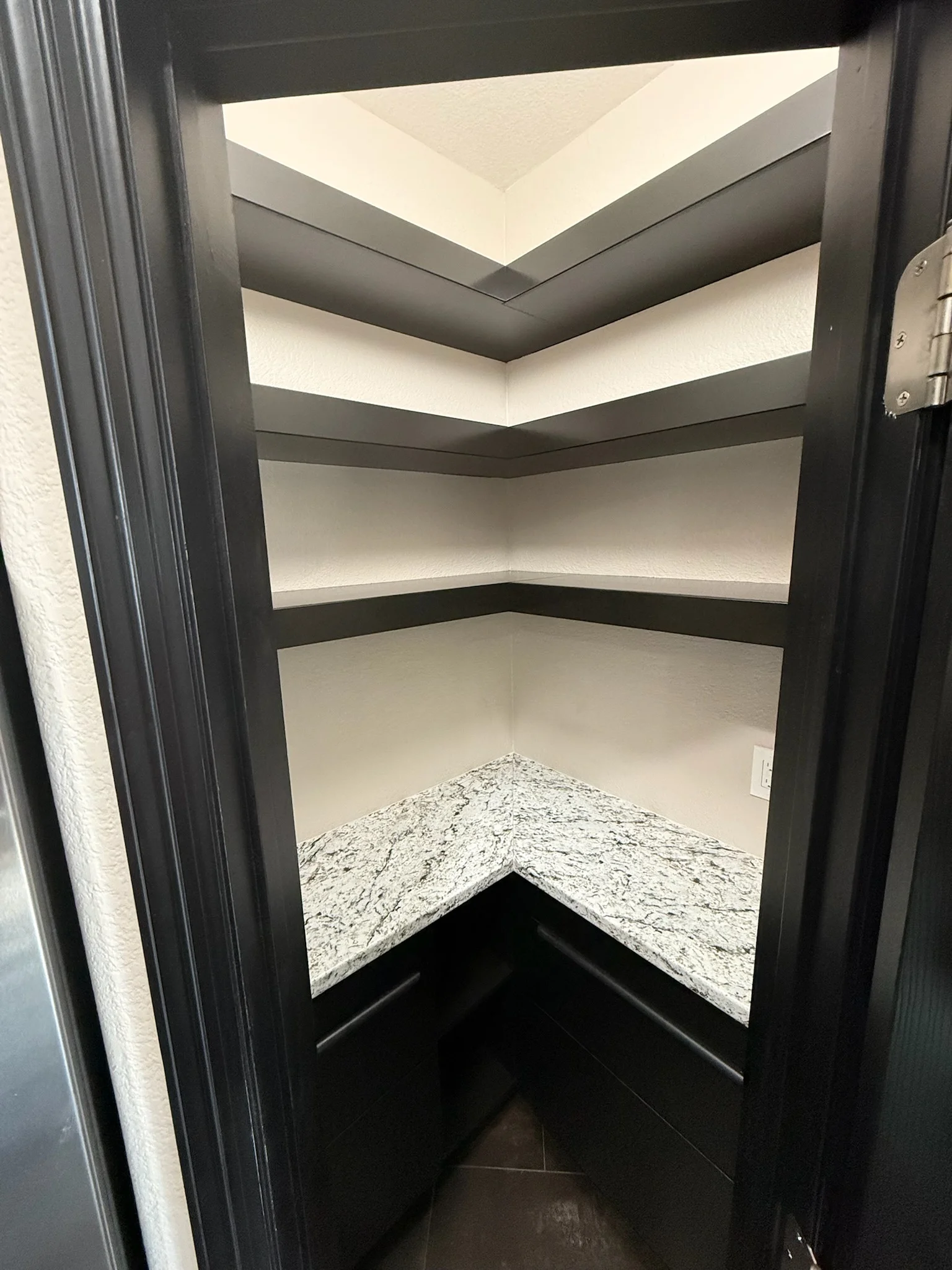 Corner shelving with three lit shelves, black trim, and granite countertop