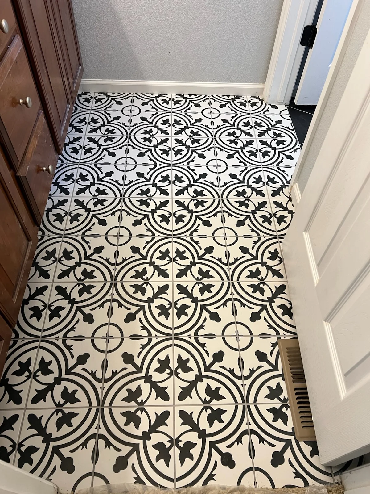 Black and white patterned ceramic tile floor with geometric and floral designs in entryway