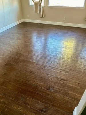 Newly installed hardwood flooring with medium-brown finish in residential room with windows