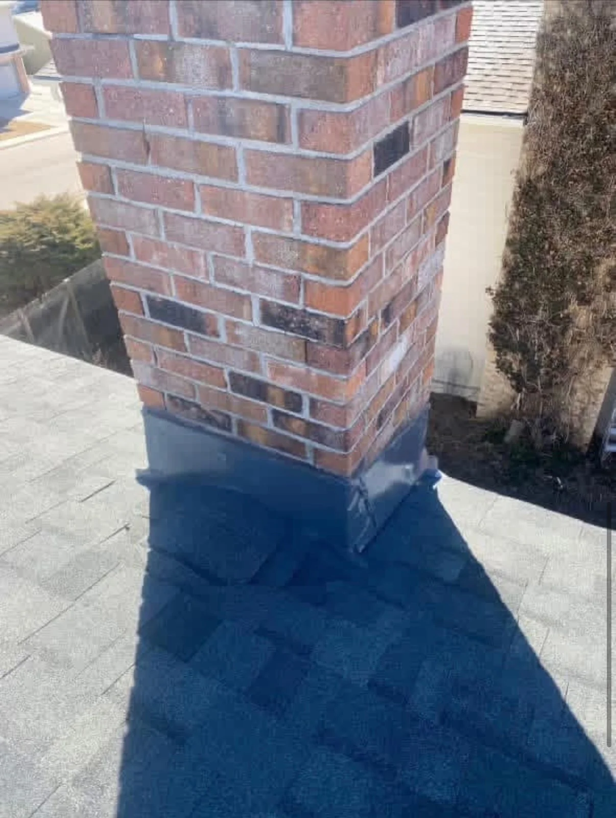 Brick chimney with fresh mortar joints and waterproof sealant applied to base