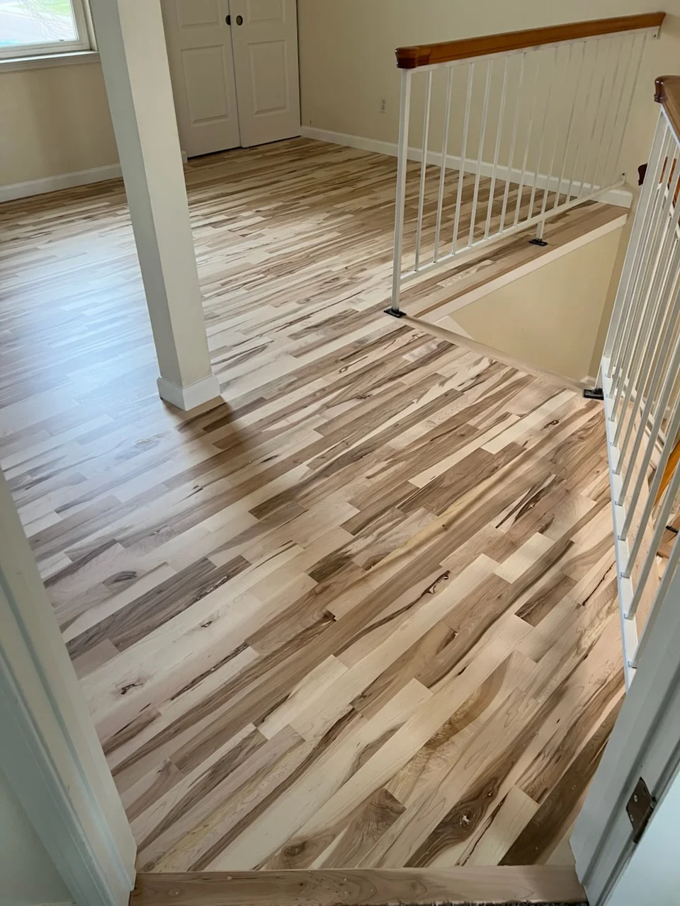 Mixed-width hardwood flooring with varied wood tones and natural grain patterns installed throughout open room space