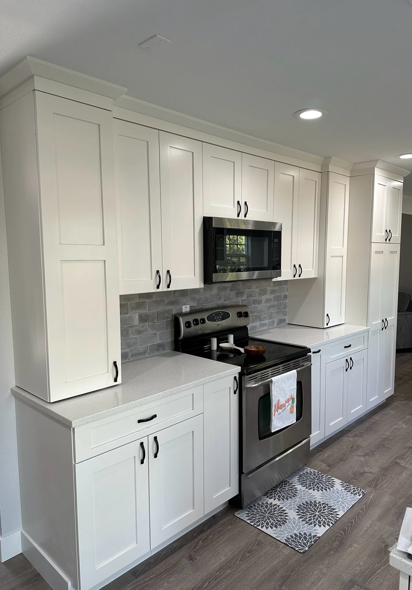 White kitchen cabinets, gray subway tile backsplash, black stainless steel range, and built-in TV niche