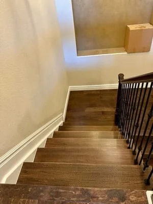 Wooden staircase with black metal railing and newly finished walls and flooring