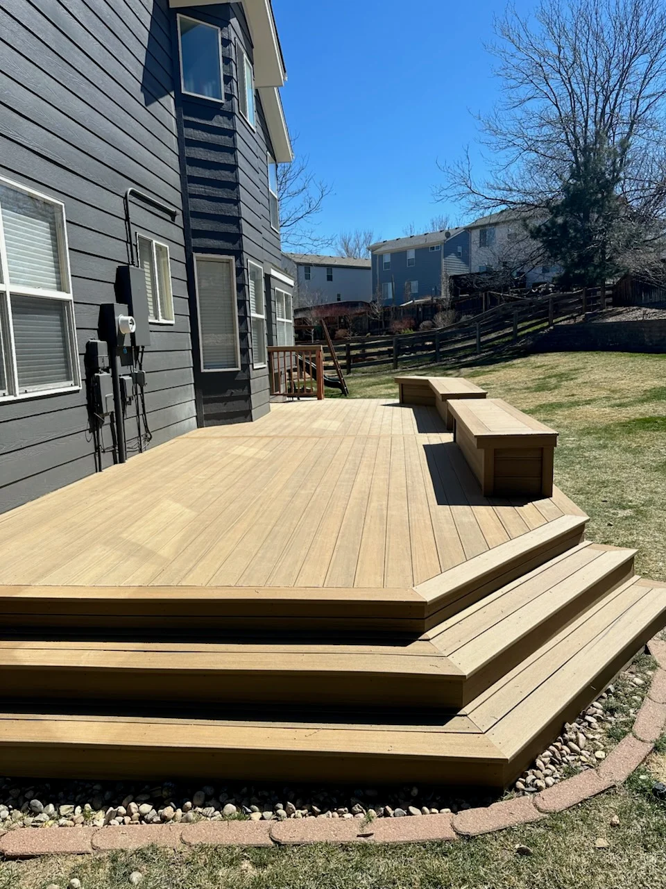 Composite deck with built-in benches, tiered steps, and gravel edging