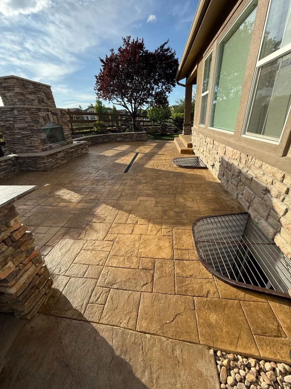 Stamped concrete patio with stone fireplace, stone veneer siding, and outdoor seating area