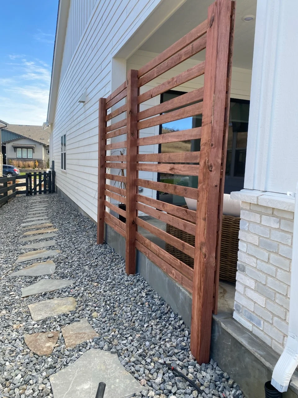 Horizontal cedar wood privacy screen with stained finish installed on residential exterior