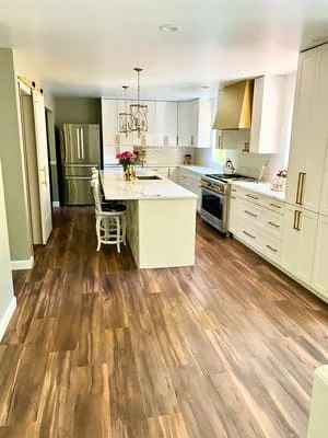 Modern white kitchen with island, quartz counters, and wood-look flooring