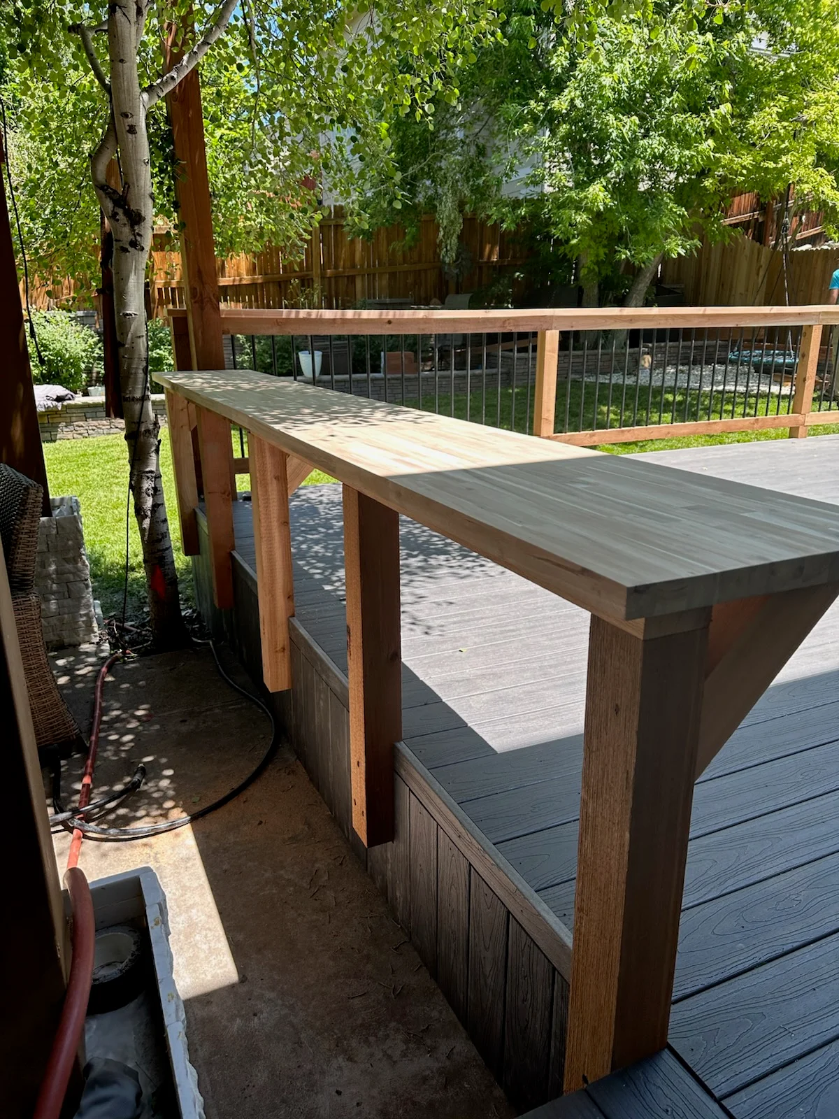 Composite deck with wood-framed bar counter, metal railings, and mixed-tone decking boards