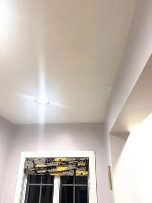 Newly installed white drywall ceiling with recessed lighting and soffit detail