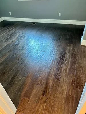 Dark hardwood flooring with glossy finish installed in residential room with white baseboards