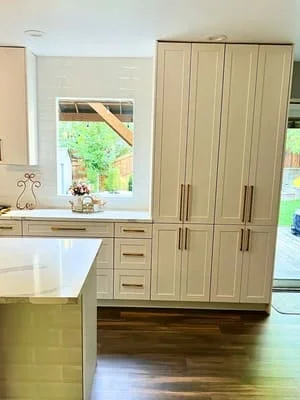 Modern kitchen with cream cabinetry, white island countertop, and hardwood floors