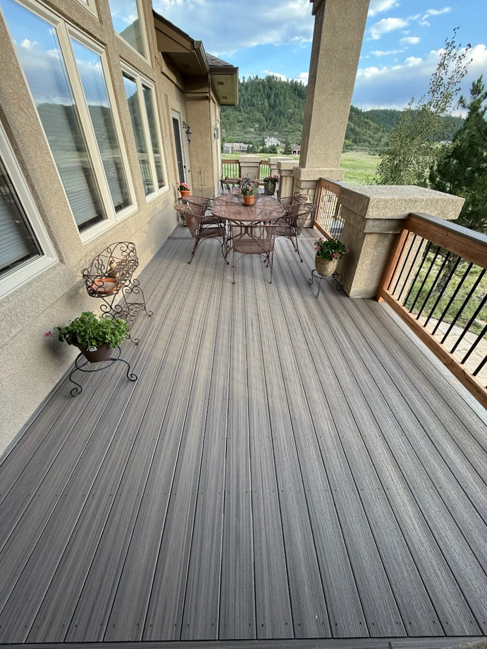 Gray composite deck with metal and wood railing, concrete columns, and stone veneer