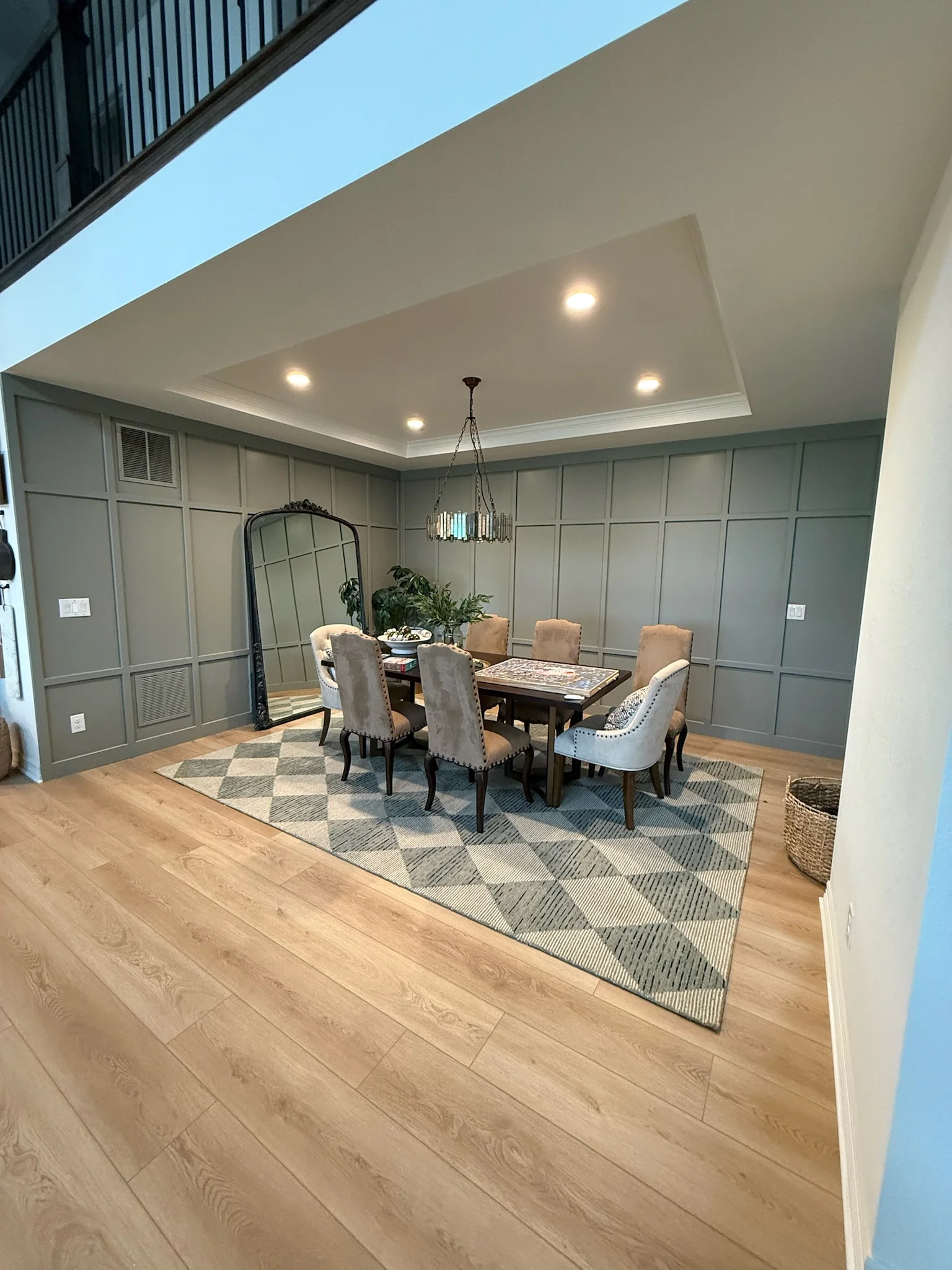 Dining room with coffered ceiling, recessed lights, sage green shiplap walls, wood flooring, and dining furniture