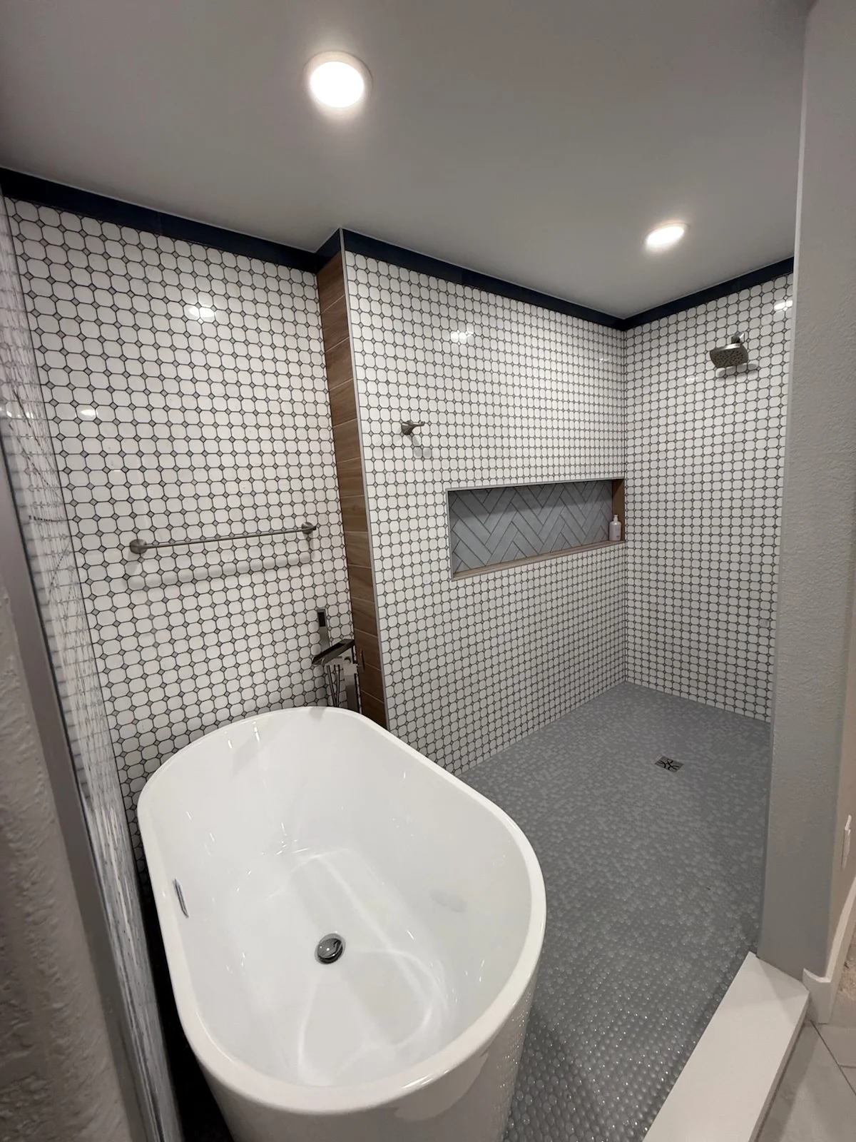 Bathroom with white soaking tub, penny tile walls, herringbone niche, and gray hexagonal floor tile