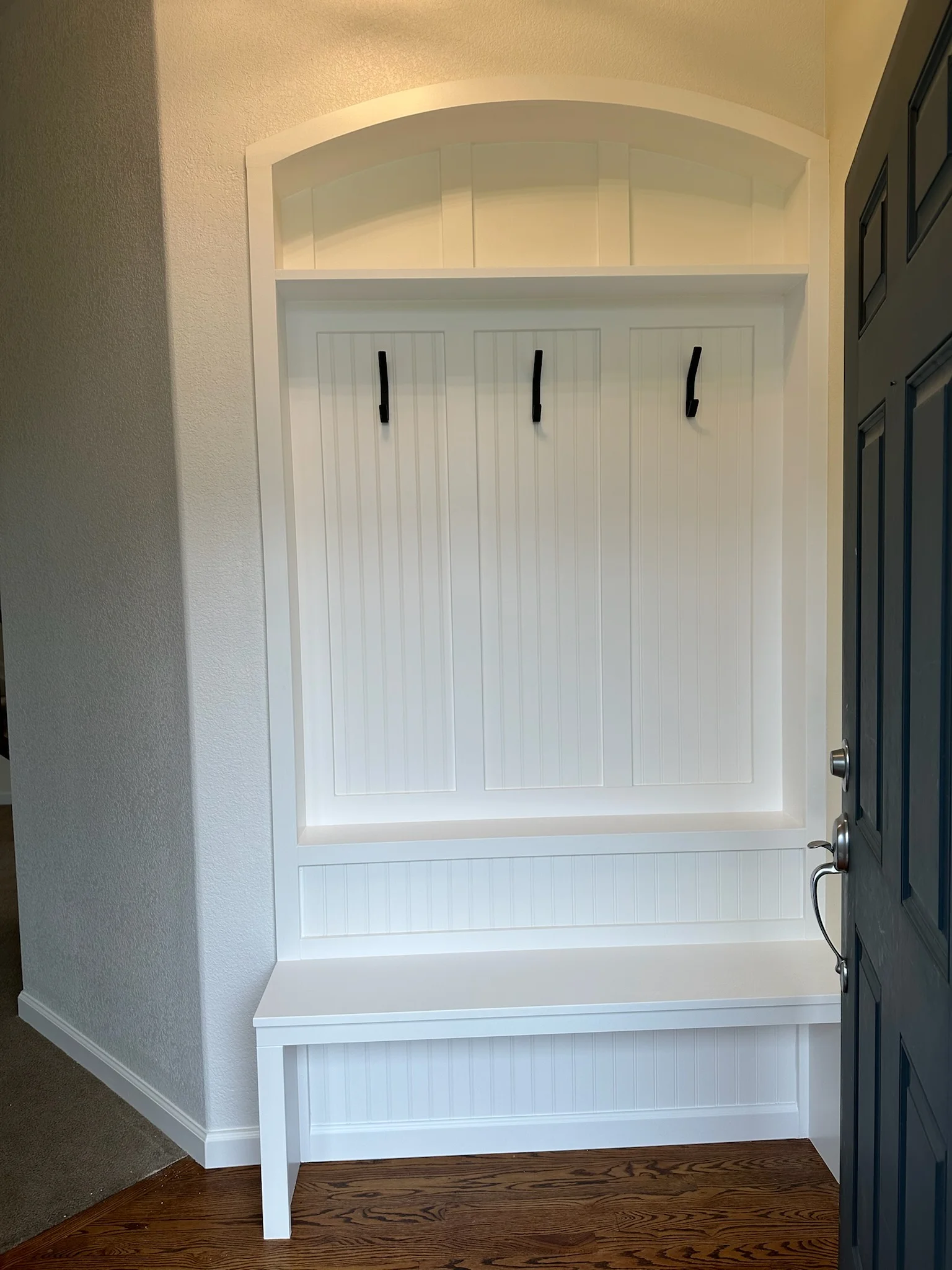 White painted garage door surround with arched transom, vertical shiplap panels, and built-in bench seating