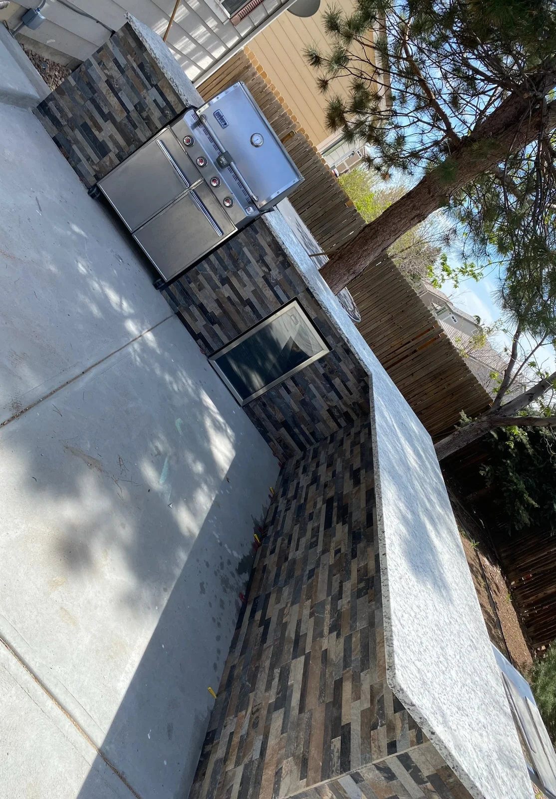 Patterned brick patio with stainless steel grill and concrete pad installation