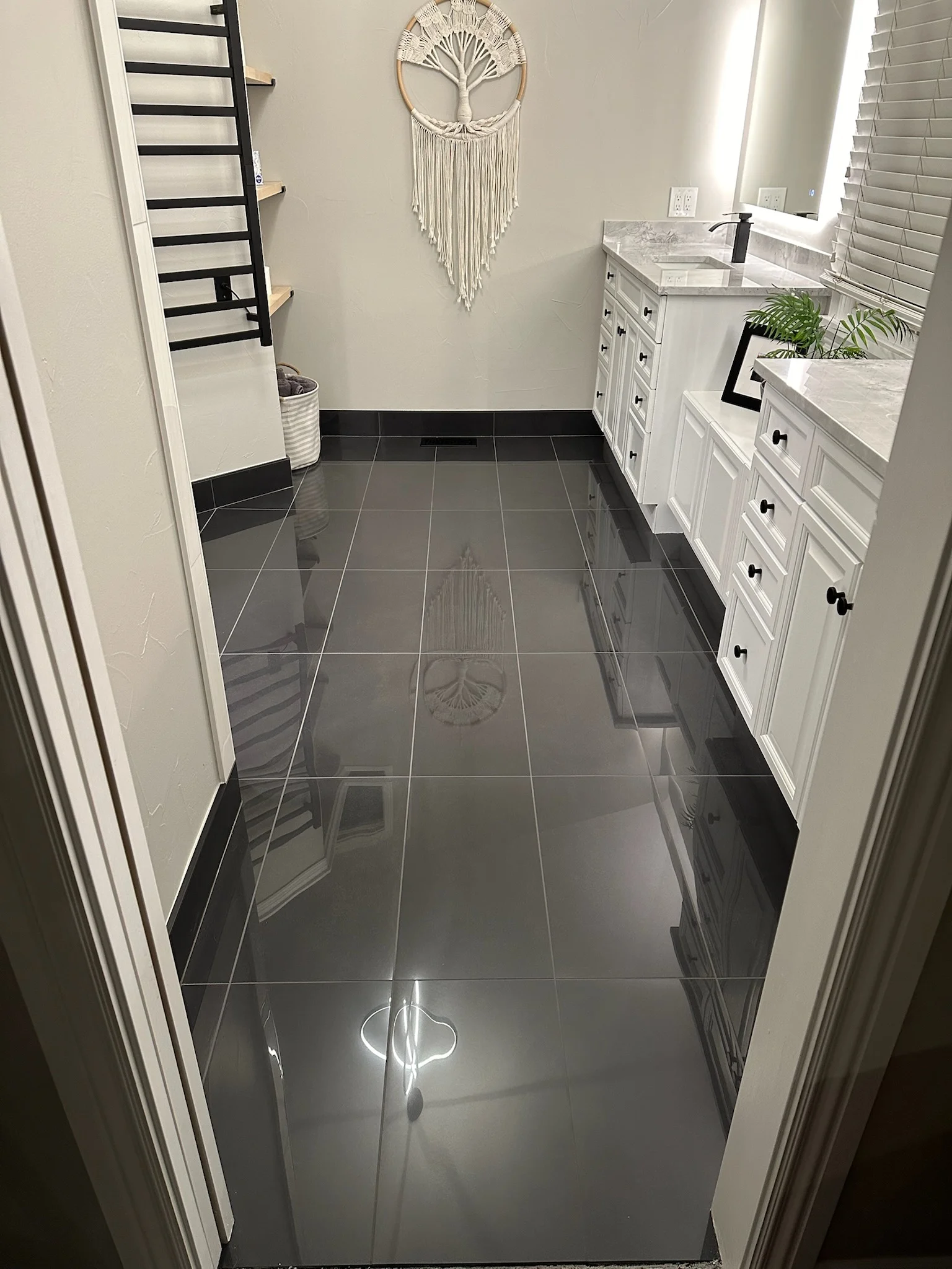 Dark gray polished tile flooring, white cabinetry, marble countertops in modern bathroom