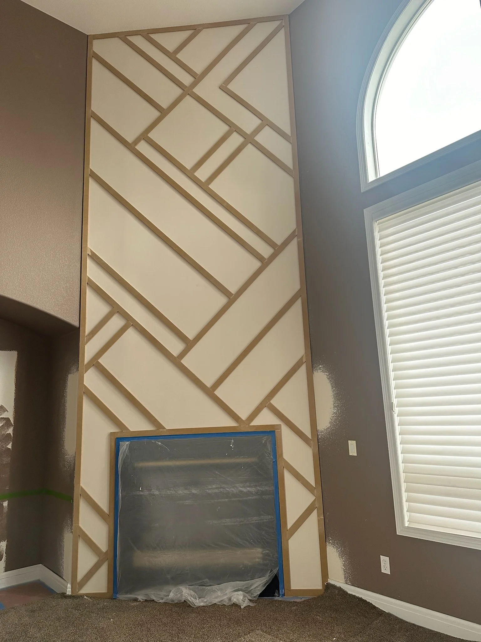 Geometric drywall feature wall with wood lattice trim in herringbone pattern, floor to ceiling installation