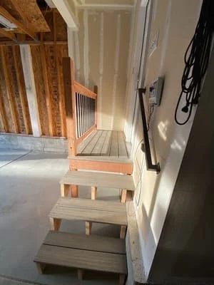 Wooden staircase under construction with exposed framing and finished treads in interior home renovation