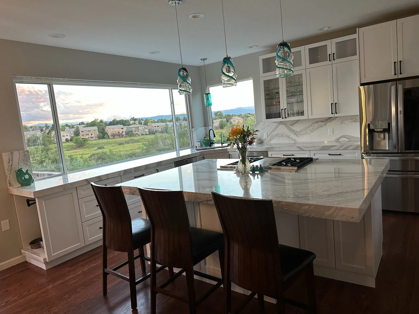 White kitchen with marble island, stainless appliances, and mountain view windows