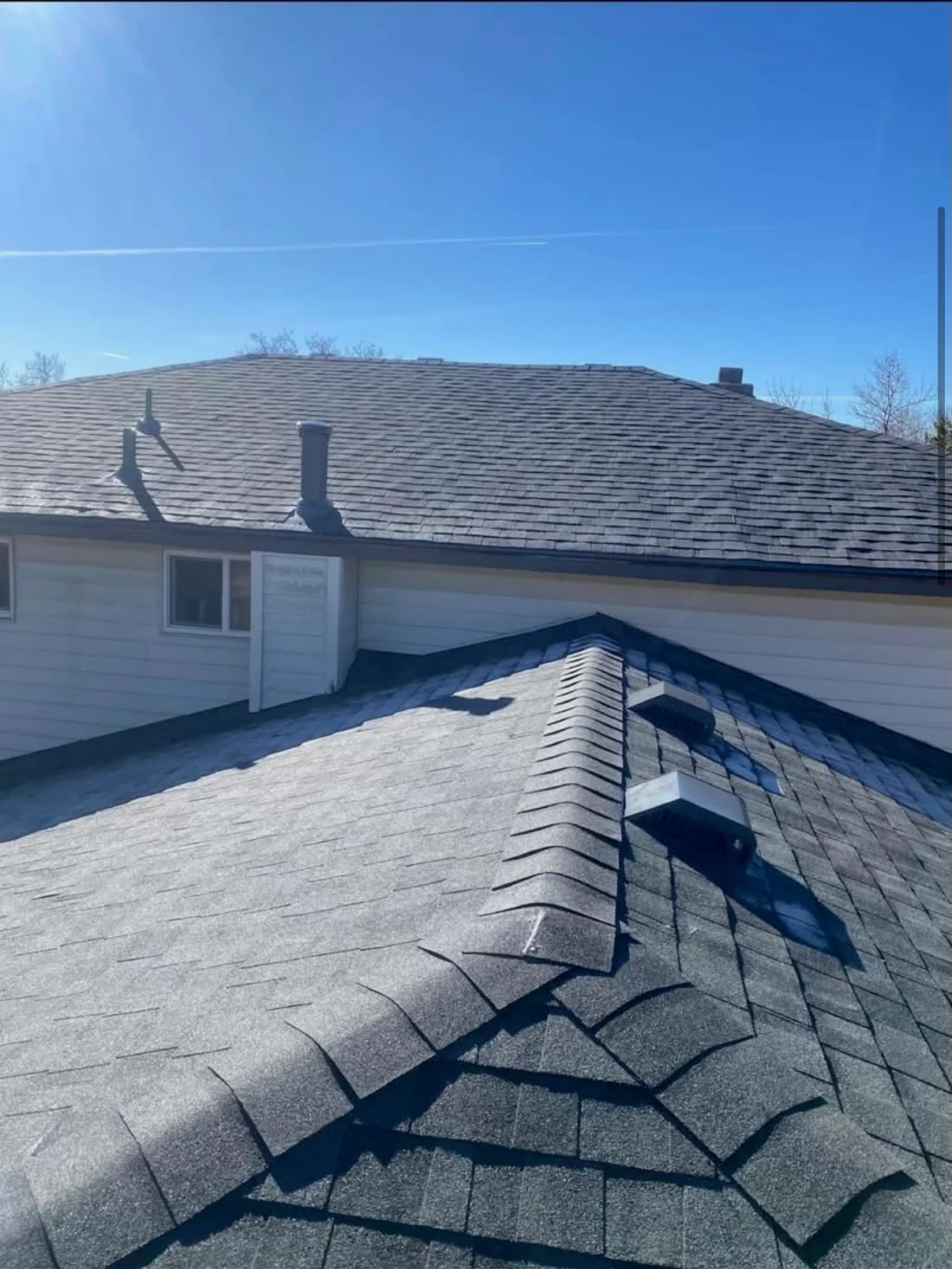 Charcoal gray architectural shingles with ridge cap and chimney flashing on residential roof