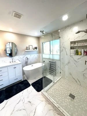 Modern bathroom with white vanity, freestanding tub, and marble walk-in shower
