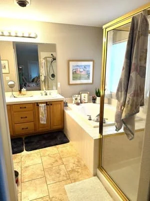 Renovated master bathroom with wood vanity, granite counters, tile flooring, and glass shower