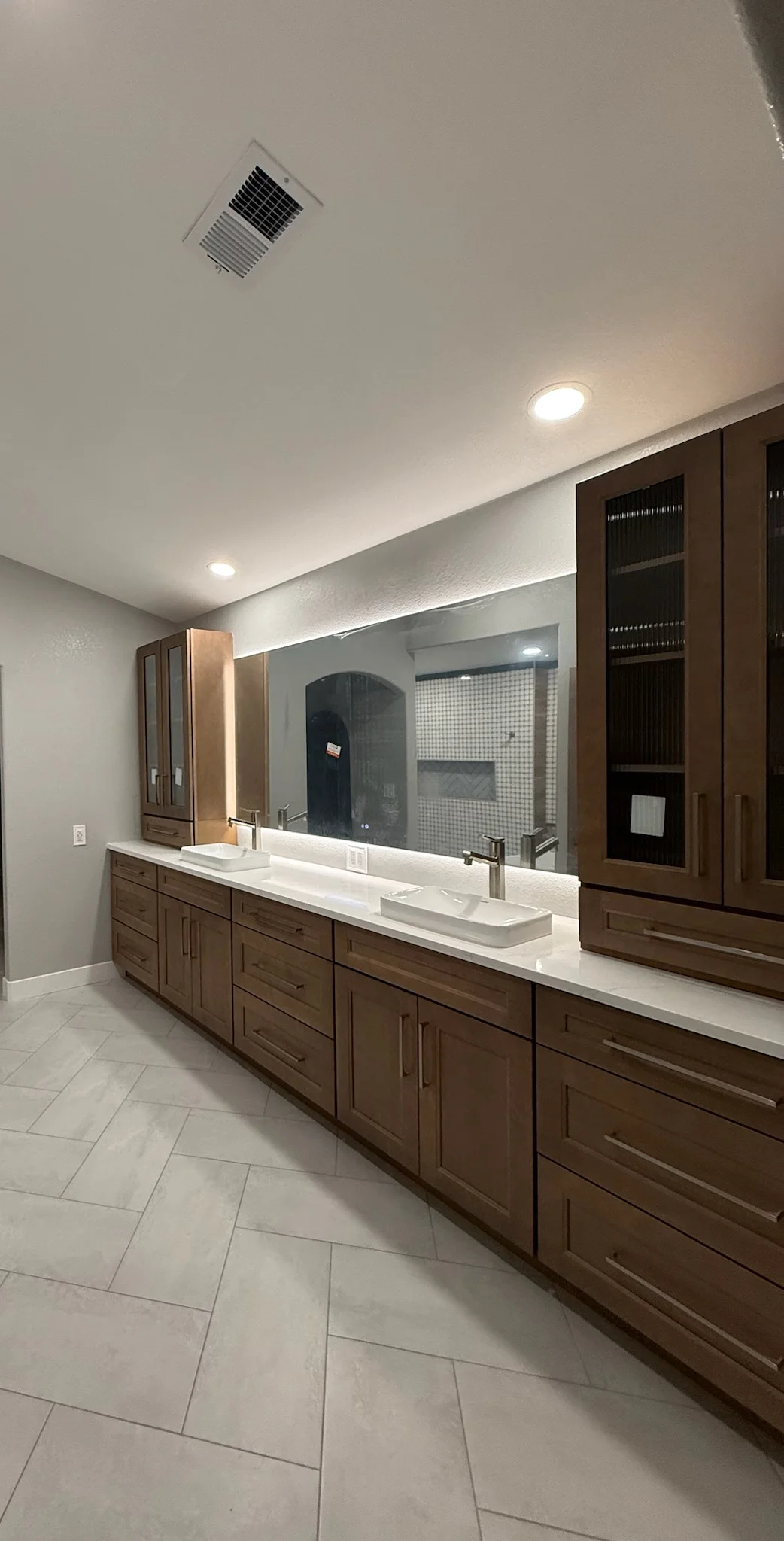 Master bathroom with dark wood cabinets, white quartz counters, dual sinks, and large mirror